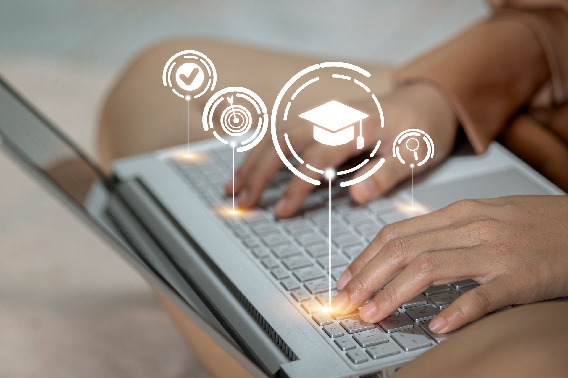 A woman is typing on a laptop with a graduation cap on the screen